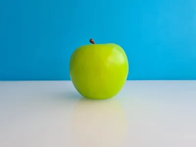 Зеленое красивое спелое яблоко на синем фоне | Премиум Фото