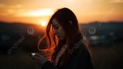 молодая девушка использует свой телефон на закате, фото красивой молодой  женщины, касающейся волос и мобильного телефона на закате, Hd фотография  фото фон картинки и Фото для бесплатной загрузки