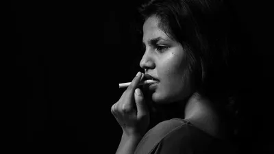 Девушка курит сигарету на фоне …» — создано в Шедевруме