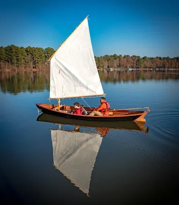 Мужчина гребет на маленькой лодке с парусом · Бесплатные стоковые фото
