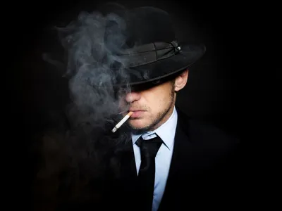 Обои на рабочий стол Мужчина в шляпе, костюме и галстуке с сигаретой во рту  на черном фоне, обои для рабочего стола, скачать обои, обои бесплатно