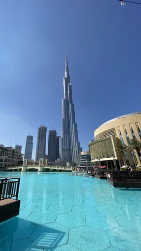 Дубай Обои на телефон большое здание с бассейном перед ним на фоне небоскреба Бурдж-Халифа