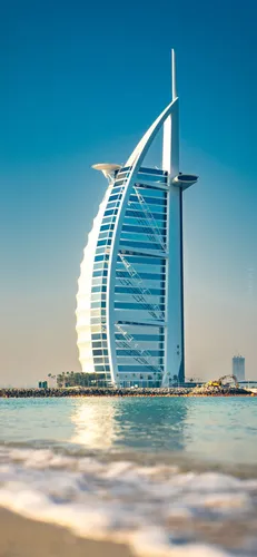 Дубай Обои на телефон высокое здание с водоемом перед ним на фоне Бурдж-эль-Араб