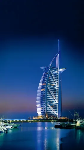 Дубай Обои на телефон высокое здание с заостренной вершиной и водоемом на переднем плане с Бурдж-эль-Араб на заднем плане