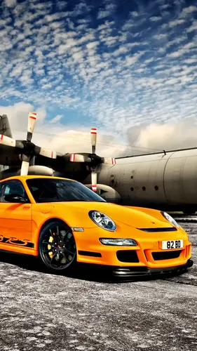 Porsche 911 Обои на телефон желтый спортивный автомобиль, припаркованный рядом с большим самолетом