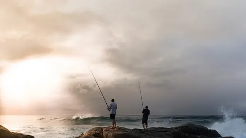 Рыбалка Обои на телефон пара мужчин рыбачит на скалистом пляже