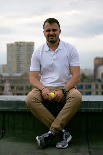 Мужчин Фото мужчина, сидящий на скамейке, держит теннисный мяч
