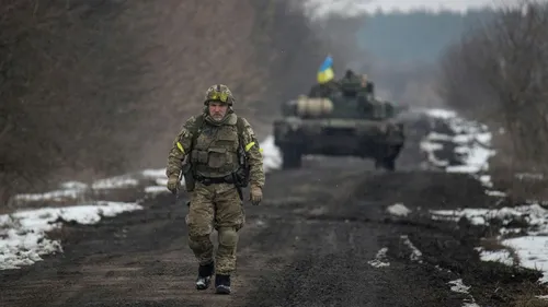 Военные Картинки человек в военной форме, идущий по грунтовой дороге с танком на заднем плане
