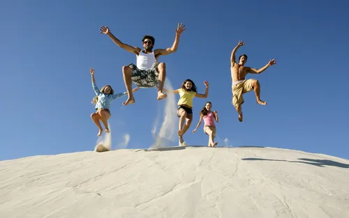 Счастливые Обои на телефон группа людей прыгает по песчаной дюне
