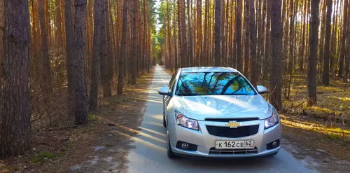 Шевроле Круз Обои на телефон автомобиль едет по дороге, окруженной деревьями