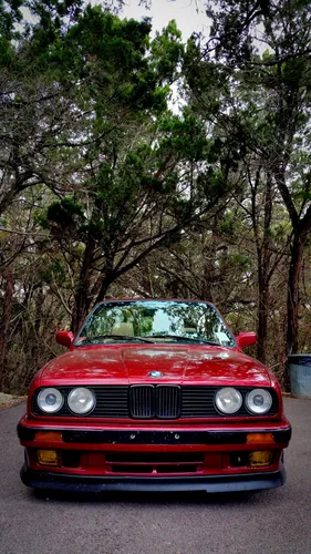 Bmw E30 Обои на телефон красный автомобиль, припаркованный перед деревьями