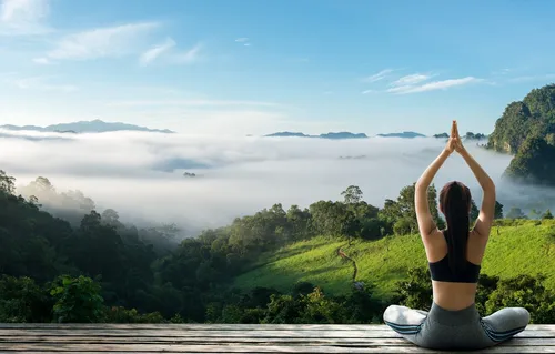 Йога Обои на телефон женщина, сидящая на выступе с видом на долину с деревьями и голубым небом
