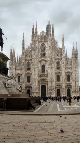 Милан Обои на телефон большое каменное здание с множеством шпилей и гуляющих людей на фоне Миланского собора