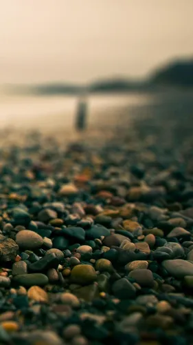 Макро Обои на телефон каменистый пляж с гуляющим по нему человеком