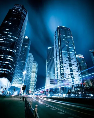 Город Ночной Обои на телефон дорога с высокими зданиями по обе стороны от нее