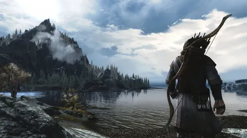 Скайрим Обои на телефон видеоигра человека, держащего меч и щит у реки с горами и деревьями