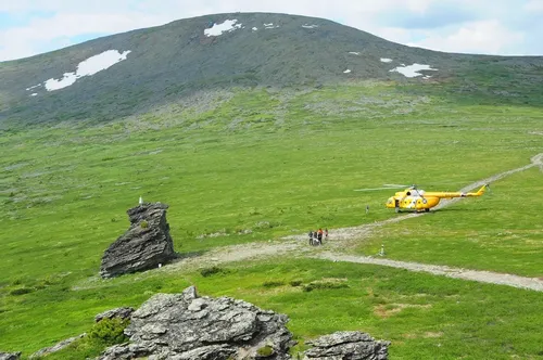 Перевал Дятлова Фото желтый вертолет, пролетающий над травянистым холмом