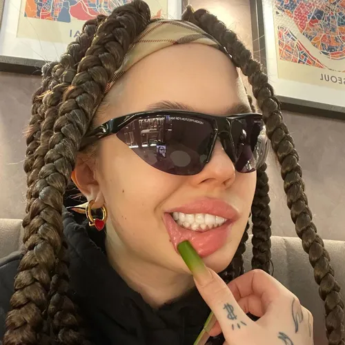 Инстасамки Фото женщина в солнцезащитных очках и держащая зеленый предмет ко рту