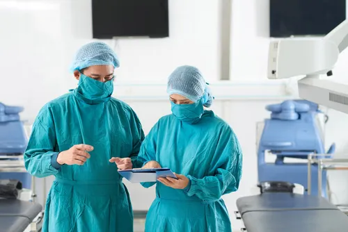 Базалиома Фото пара хирургов в синих скрабах смотрит на планшет