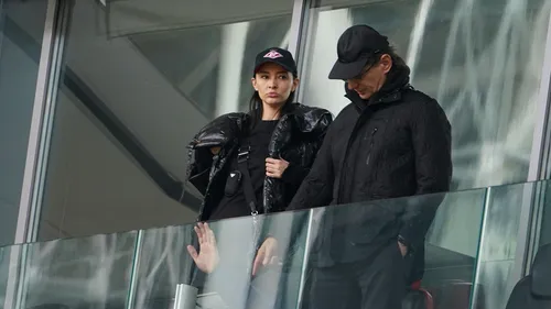 Зарема Салихова Фото женщина в черной куртке и шляпе, стоящая рядом с мужчиной в черной куртке