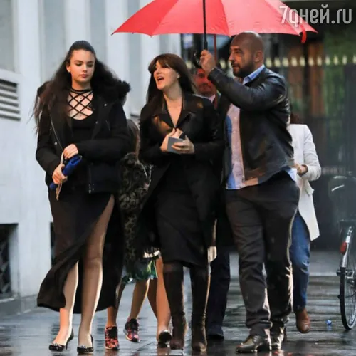 Моника Беллуччи Фото группа людей, идущих по тротуару с зонтиком