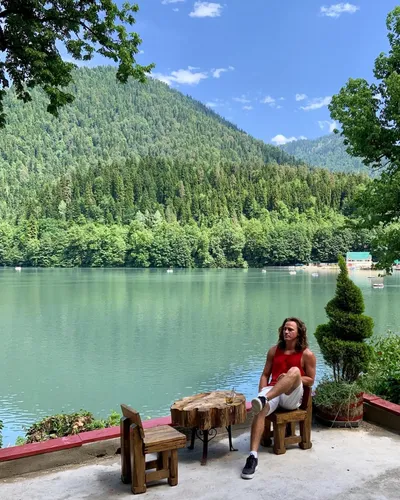 Абхазия Фото человек, сидящий на скамейке у озера