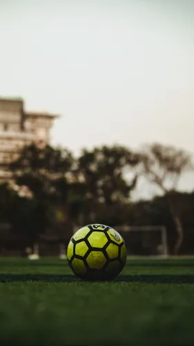 Футбольные Обои на телефон желто-черный футбольный мяч на травяном поле